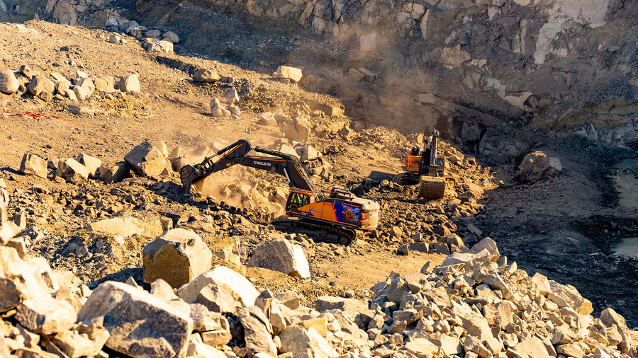 MySol excavator loading an articulated dump truck on a pit floor.